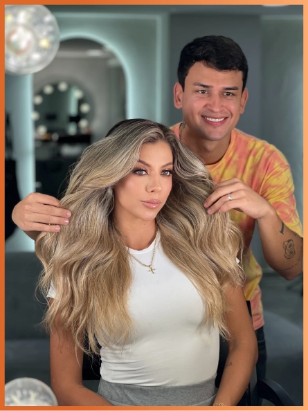 Santiago Zuluaga junto a una clienta con el cabello rubio trabajado tras una corrección de color